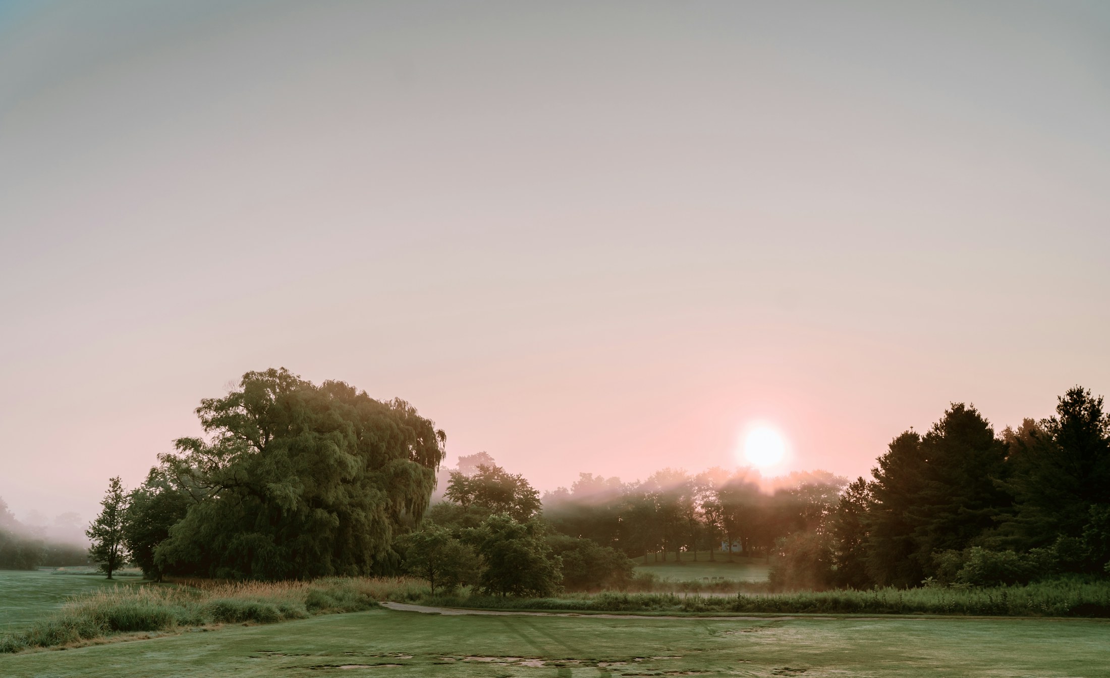 Morning mist lifting from a golf course at sunrise.